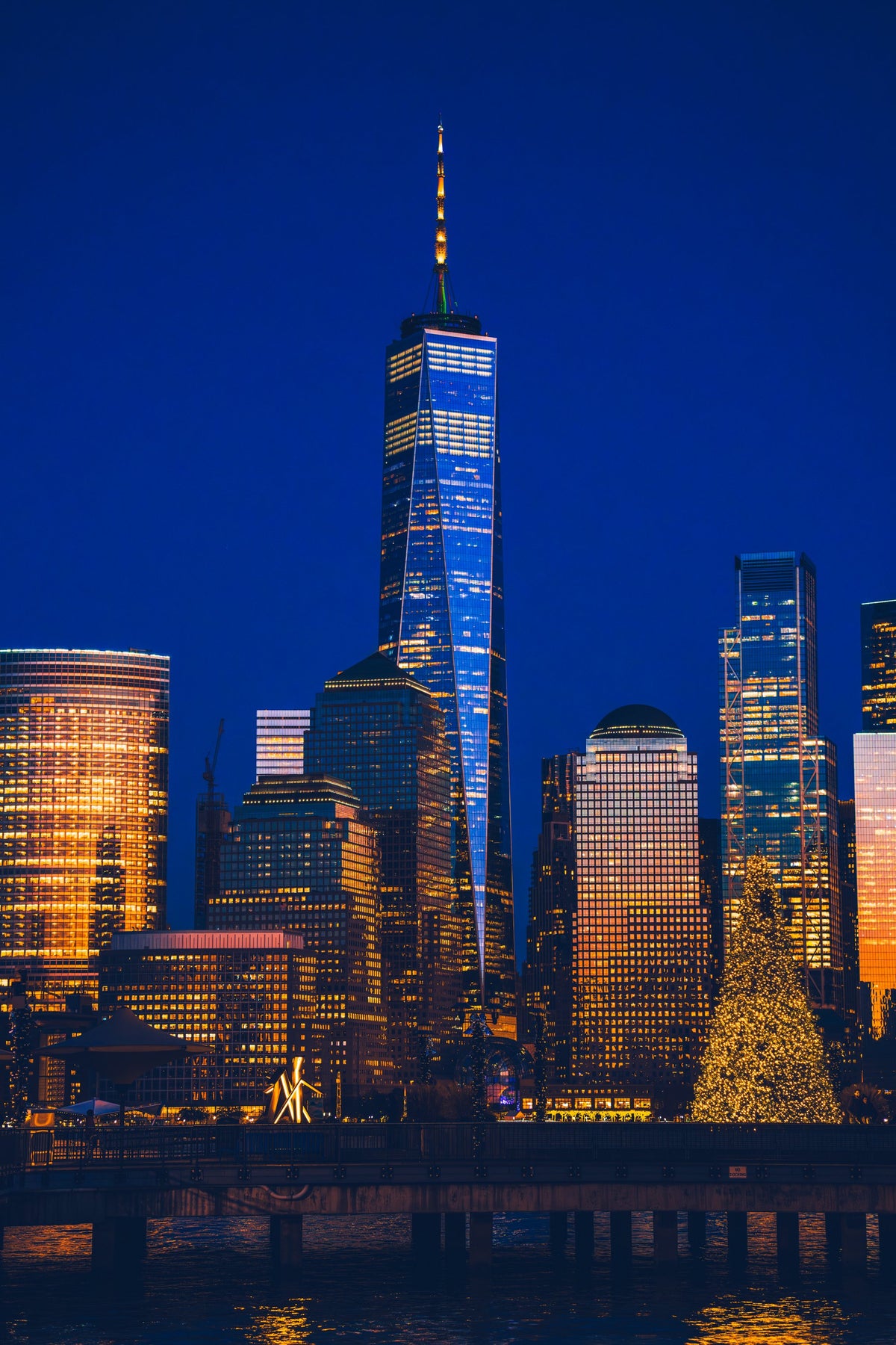 Lower Manhattan skyline and One World Trade lit blue and gold at night