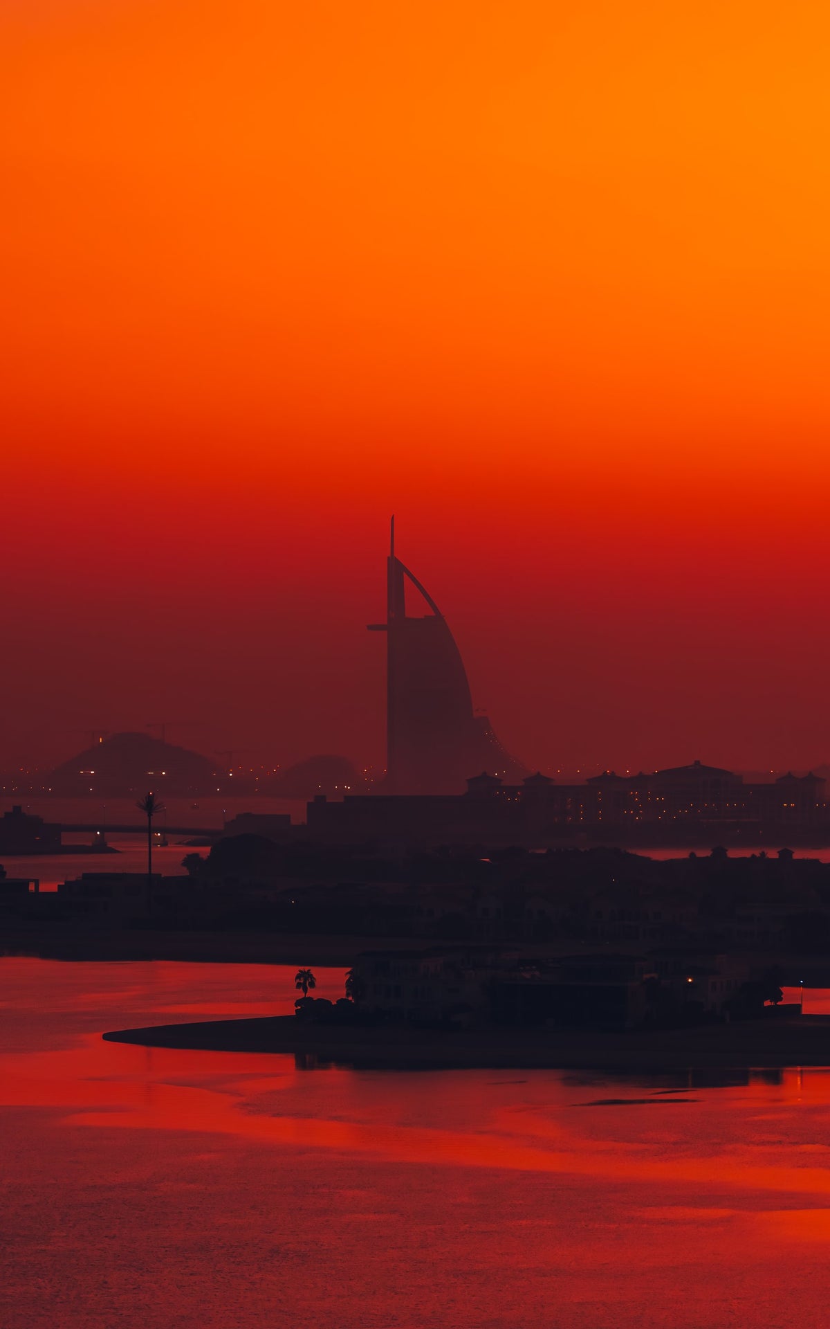 Burj Al Arab silhouetted at sunrise over red water, Dubai