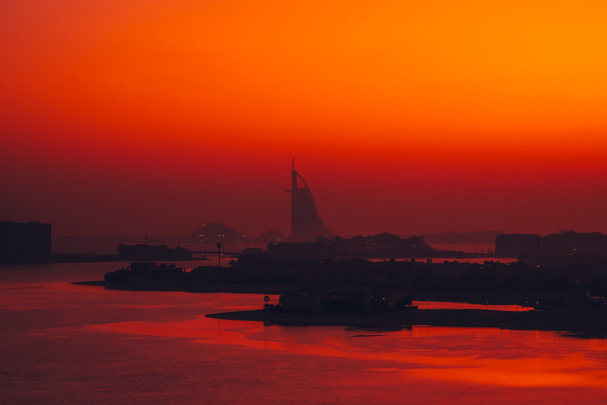 Burj Al Arab silhouetted across red water at sunrise, Dubai