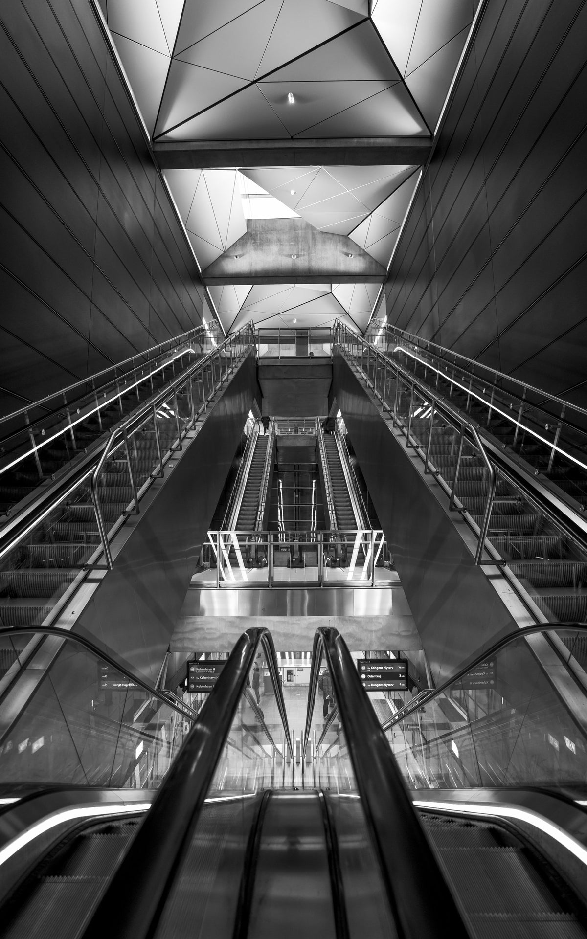 Black and white escalators and angled ceiling panels in symmetry
