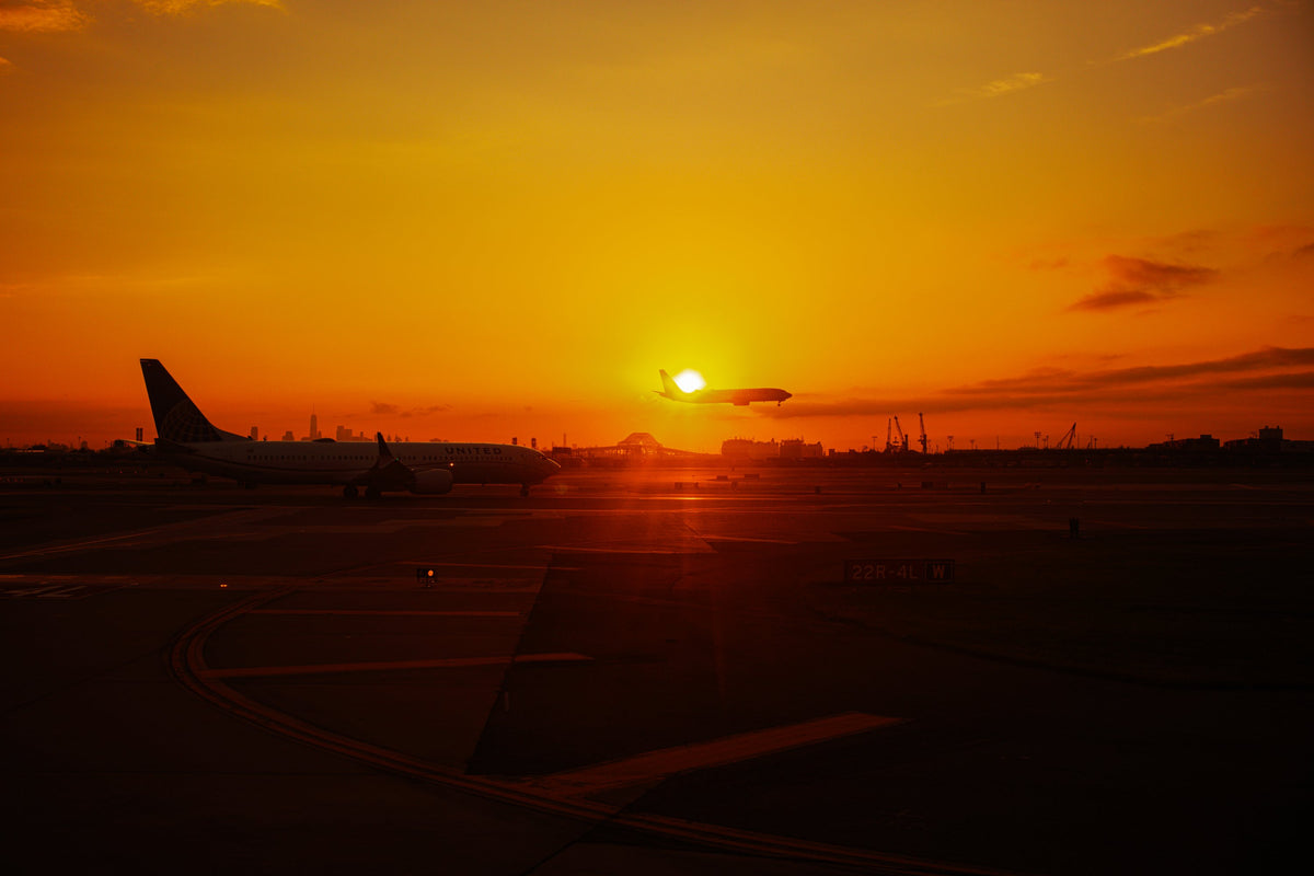 A plane in silhouette on the runway as the sun sets
