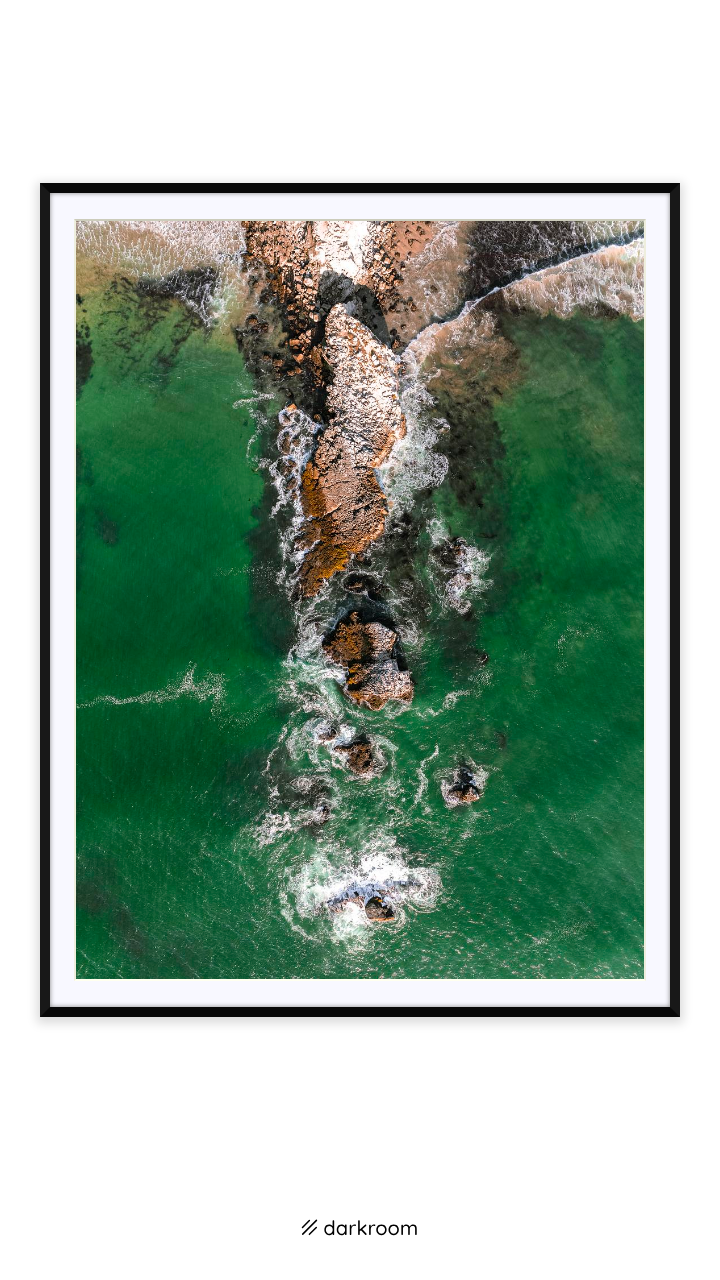 Black-framed print: Drone view of a rock ridge and breaking waves on the Pescadero coast, California