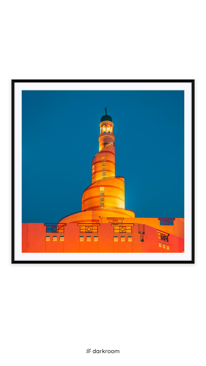 Black-framed print: The spiral minaret of the Fanar lit orange against a blue evening sky in Doha