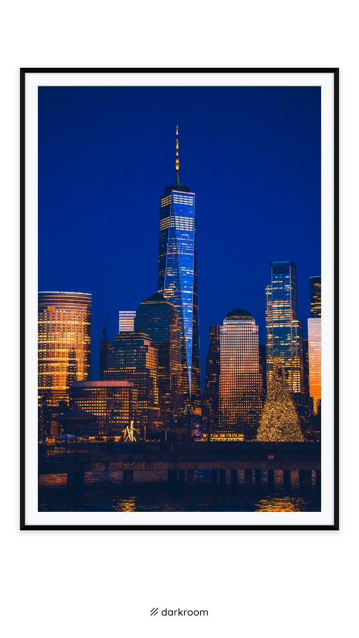 Black-framed print: Lower Manhattan skyline and One World Trade lit blue and gold at night