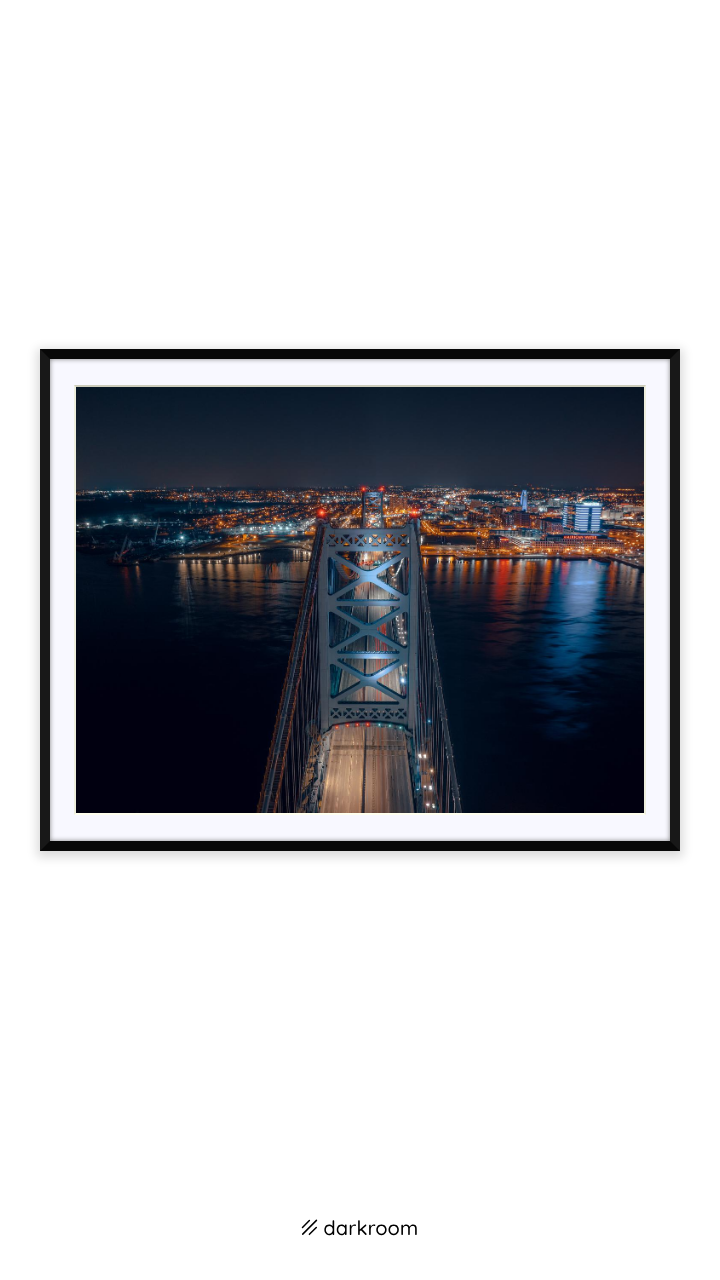 Black-framed print: Aerial night view down the Ben Franklin Bridge toward Camden, Philadelphia