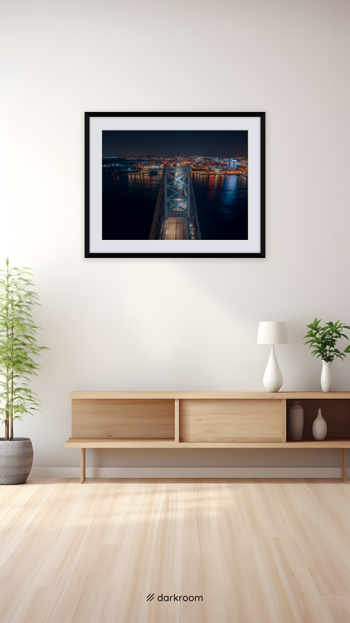 Black-framed print shown on a wall: Aerial night view down the Ben Franklin Bridge toward Camden, Philadelphia